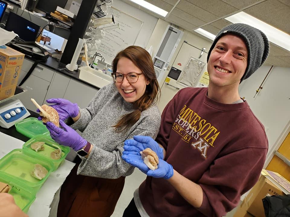 Undergraduate students holding lion brains and smiling